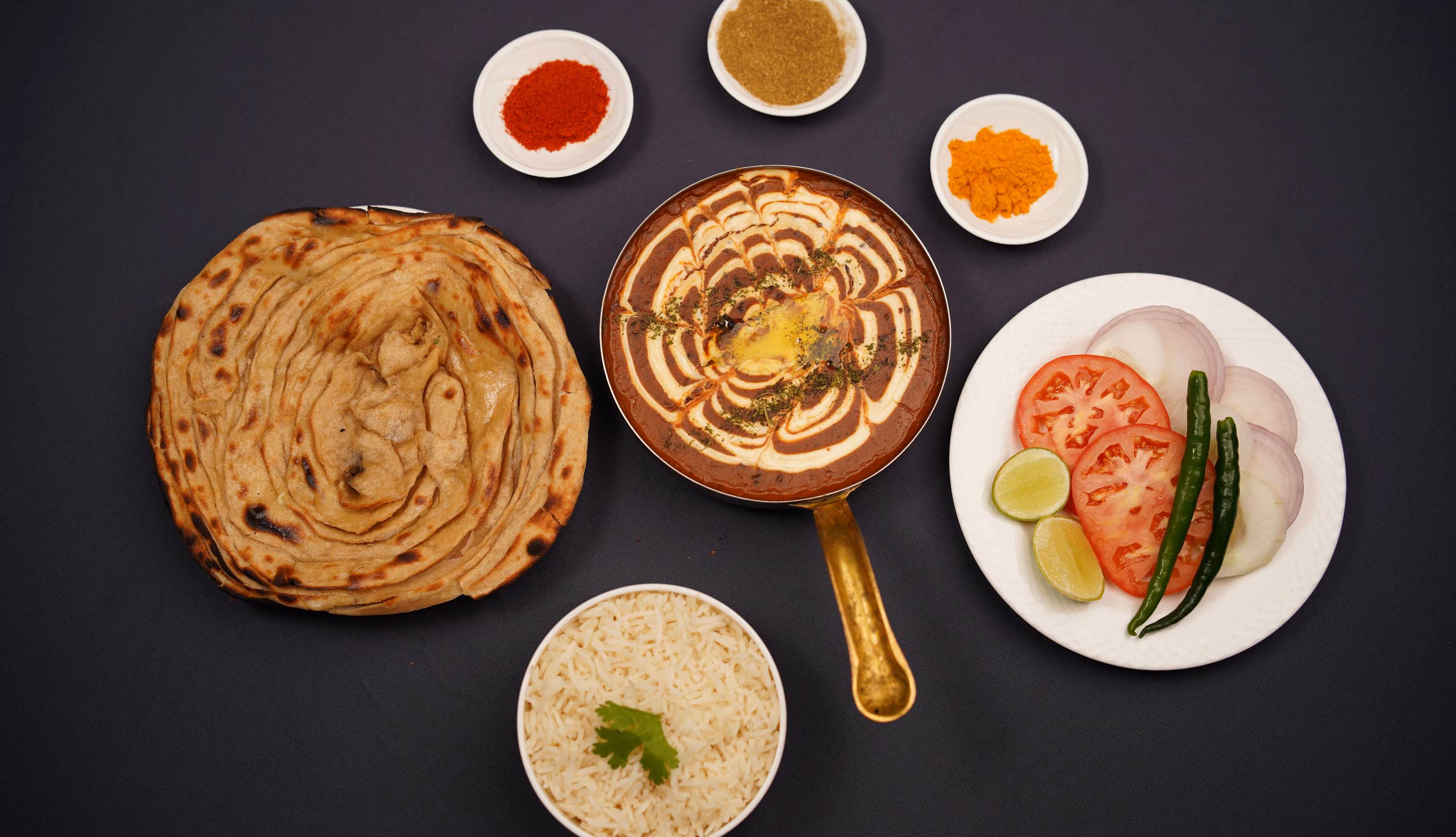 Prostřený stůl: Dal Makhani v měděné pánvi, laccha paratha, basmati rýže a čerstvá zelenina